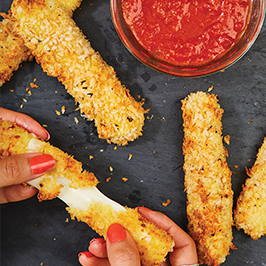 woman pulling apart a mozzarella stick with a small bowl of marinara sauce in the background