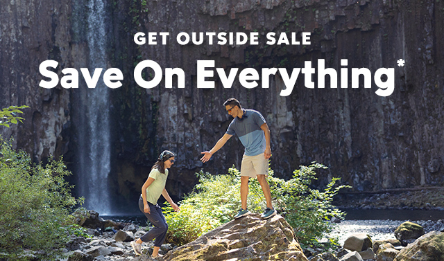 Two people hiking through a green and rocky landscape. Get Outside Sale, Save On Everything overlays the image.