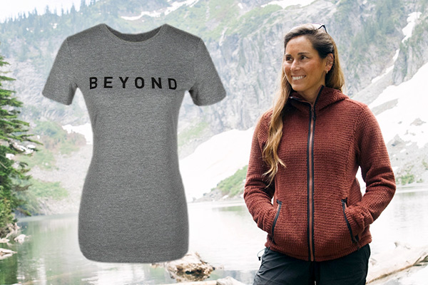 Man wearing the Mars Red Alpha Aura jacket standing in front of a mountain lake. Beyond Women's Logo tee is superimposed on the image calling attention to it.