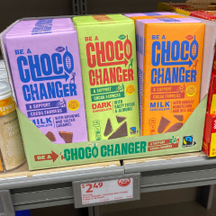 Shelf at ALDI with a cardboard display promoting Fairtrade Choco Changer chocolate bars. The 5.3 oz bars are selling for $2.49.