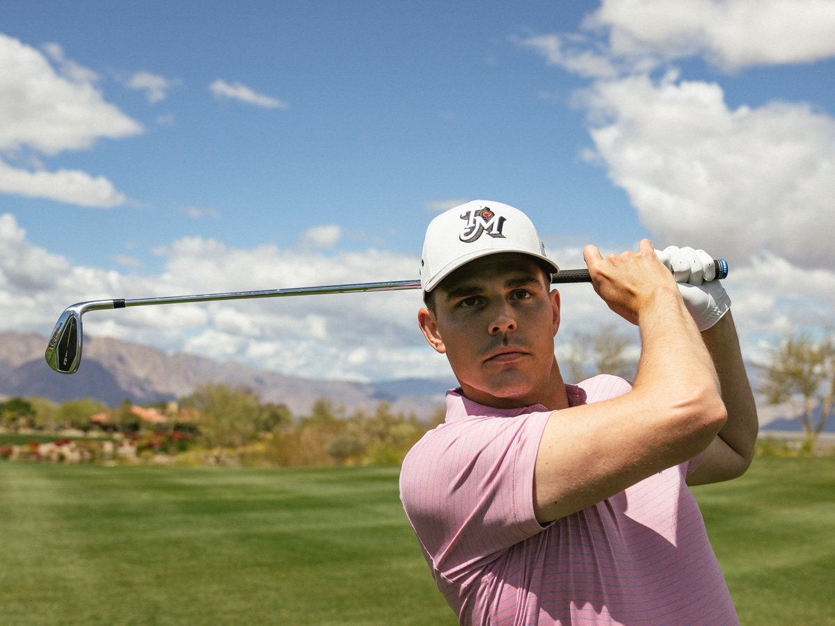 Male Golfer wearing the Daytona Rope Snapback Hat in blue and a white Tour Preferred glove, holding the bill of his hat