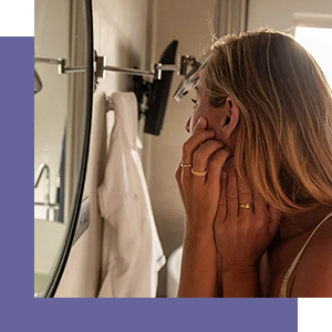 Woman examining skin in mirror