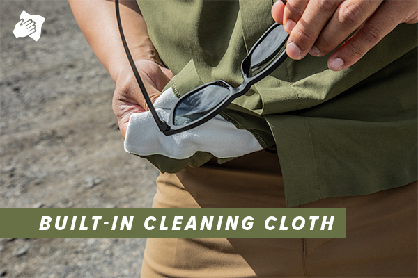 Close up photo of a man using the built in cleaning cloth on a pair of sunglasses while wearing the First Sun Short Sleeve shirt in Evergreen