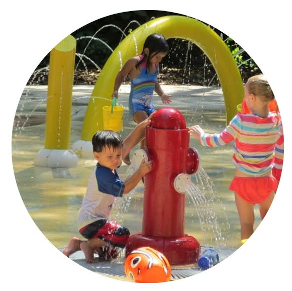 A group of children splash in water at a water park