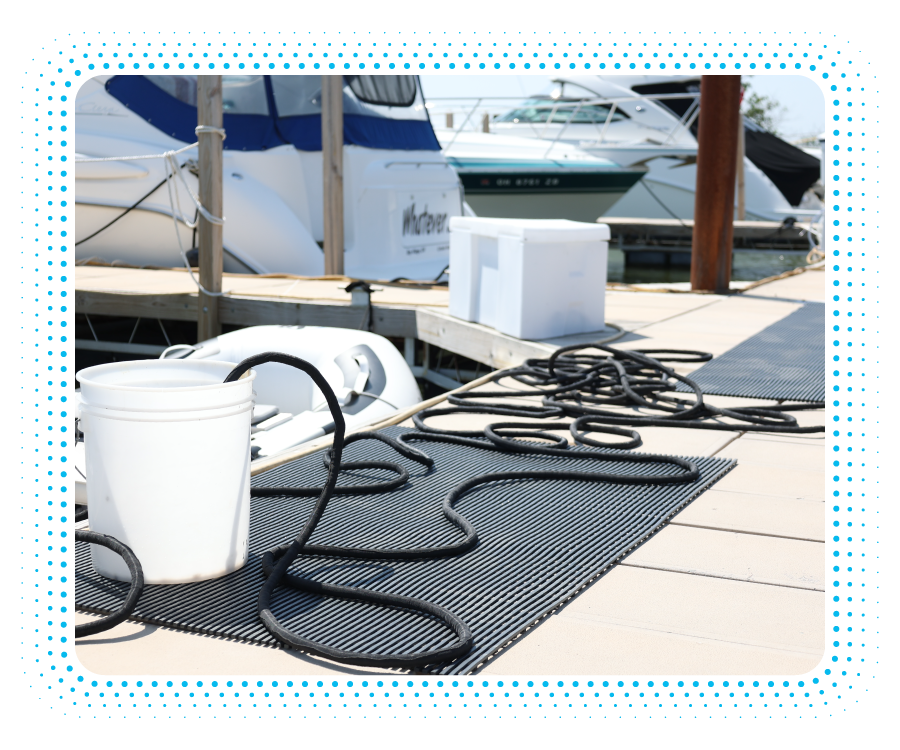 a white bucket with black rope on a mat on a dock with boats in the background