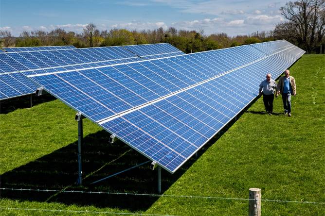 Two men walk alongside solar panels