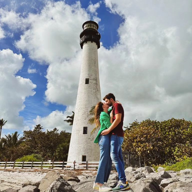 A couple kissing in front of a lighthouse