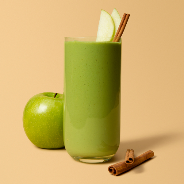 Smoothie in a single glass with apple and cinnamon sticks.