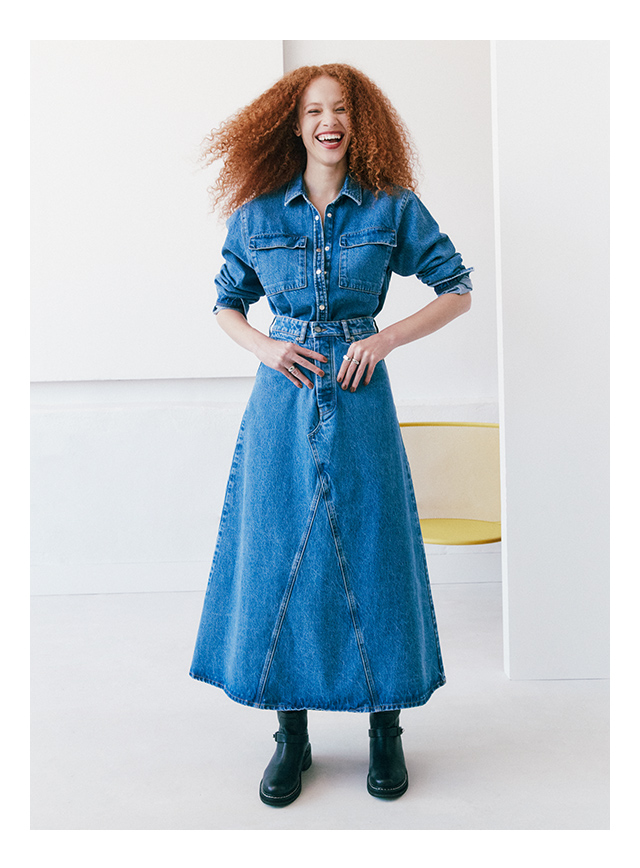 A woman wearing a denim shirt and skirt.