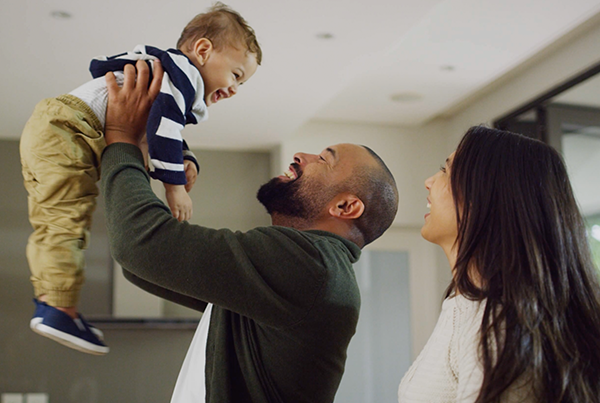 Two young parents holding smiling toddler