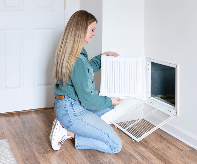 Image of woman holding air filter in front of vent