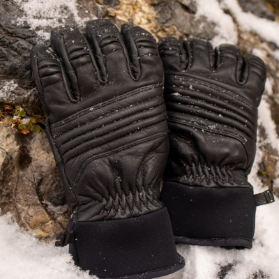 Black Guide Gloves leaning against a rocky outcropping in the snow