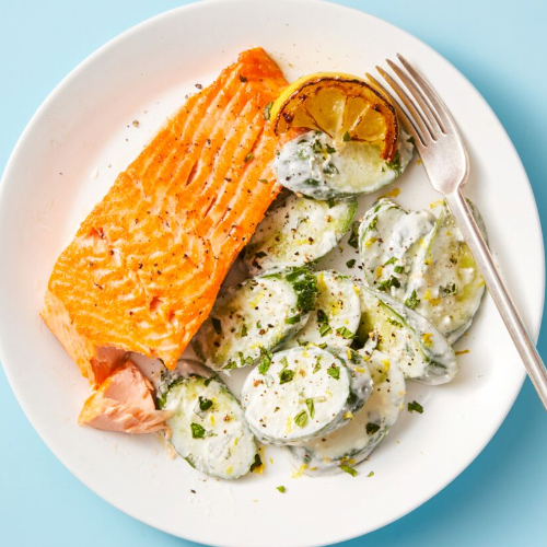 Salmon with Creamy Feta Cucumbers on a white plate with a fork