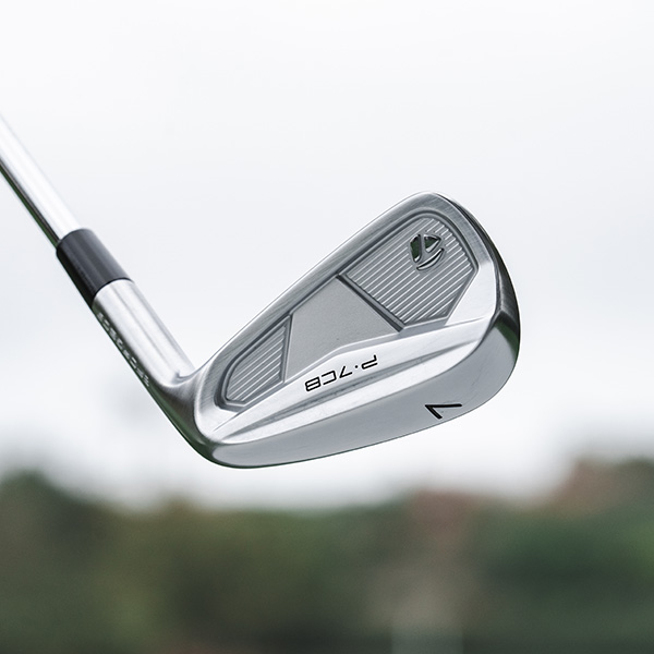 P·7CB 7 iron on range with a down range view blurred in the background