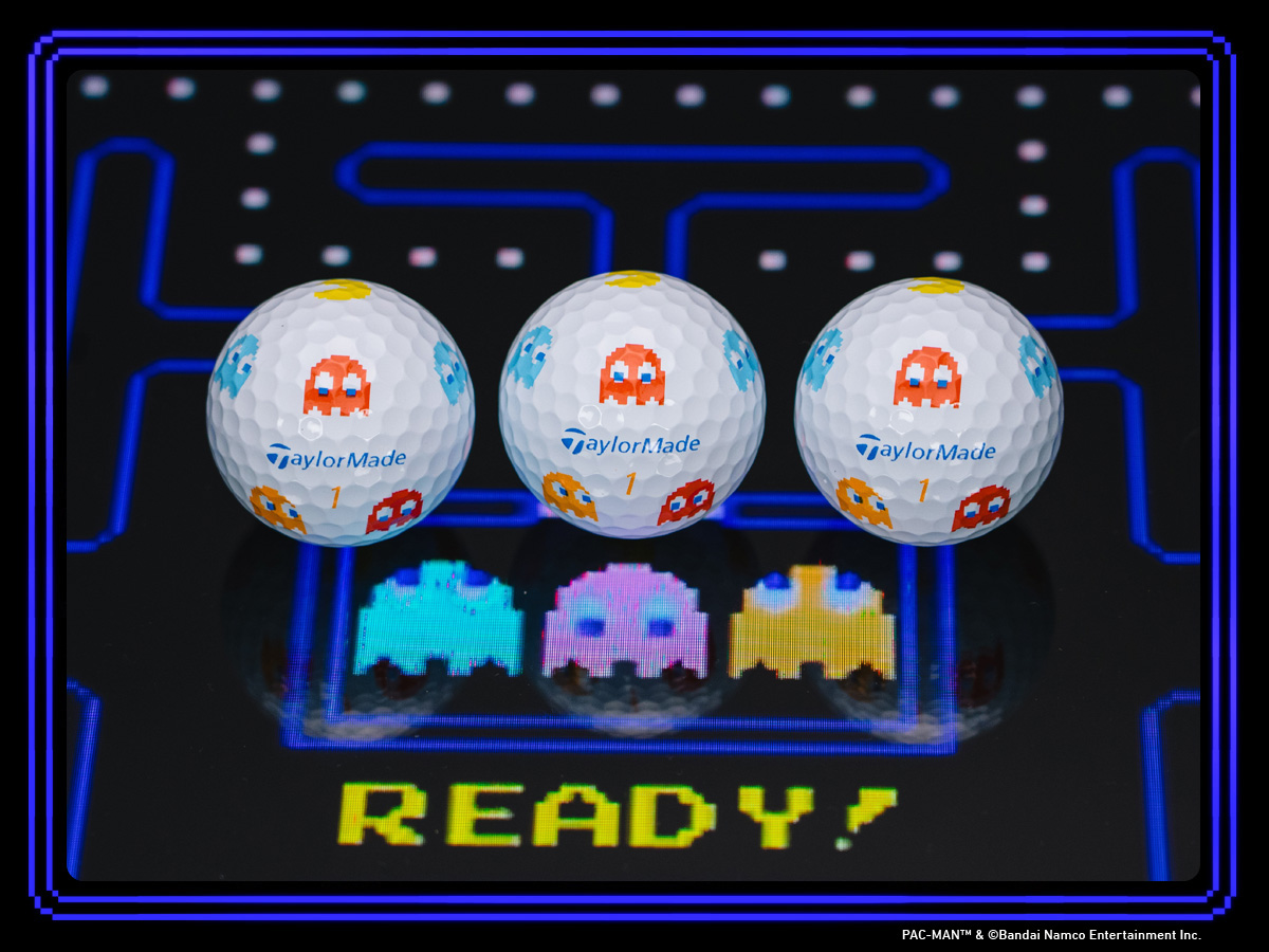 Full set of accessories in the TaylorMade | PacMan collaboration, laid out on a PacMan themed table, including the hat, visor, alignment stick, two putter headcovers, balls, tees and ball marker box