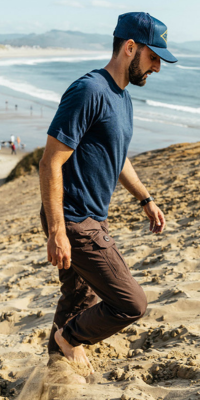 Man wearing the Navy Todra walking up a sand dune on the beach with the ocean in the background